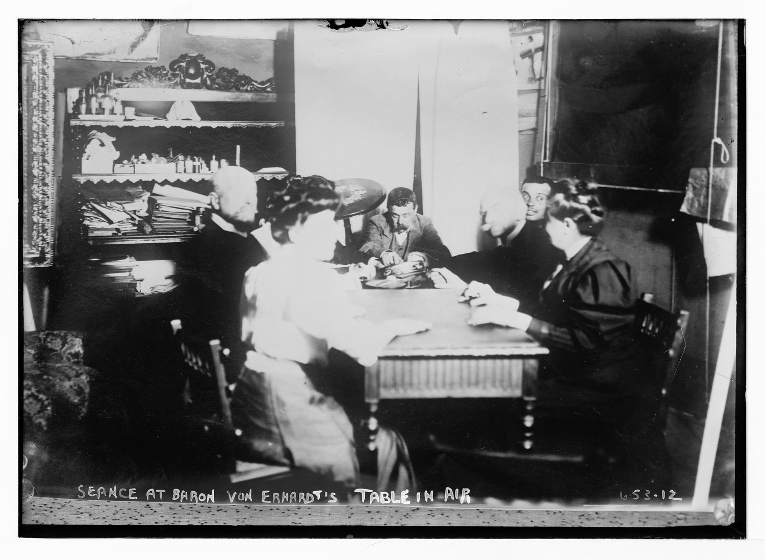 An early twentieth century photograph of a seance with a table apparently in mid air